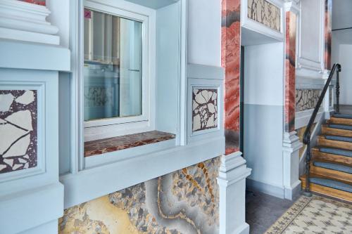 a hallway with blue walls and stairs with windows at Schwanthaler Hof in Munich