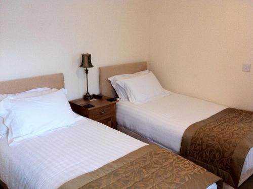 a hotel room with two beds and a night stand at Churchills Inn & Rooms in Bowness-on-Windermere