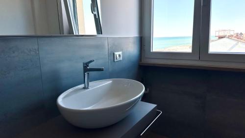 Un lavabo blanco en un baño con ventana. en P022 - Porto Recanati, nuovissimo bilocale fronte mare, en Porto Recanati