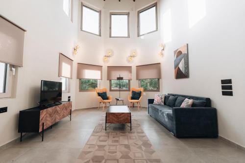 a living room with a couch and a tv and windows at Villa Di Leon - Uniquely Designed Villa with Pool in a Picturesque Village near Famous Porto Limnionas, Offering Exceptional Hospitality By Villa Mana Gers in Agios Leon
