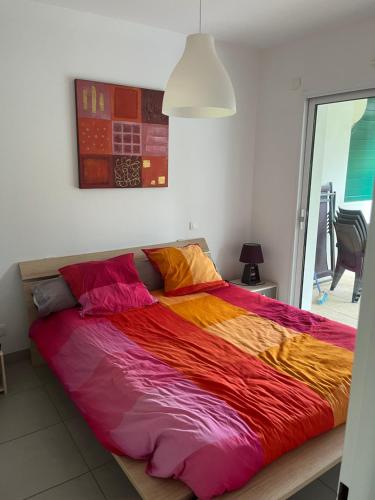 un grand lit avec des draps colorés dans une chambre dans l'établissement Appartement, à Capbreton