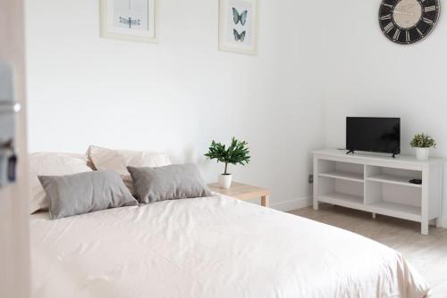une chambre blanche avec un lit blanc et une télévision dans l'établissement Aurore - Studio 24, à Carcassonne