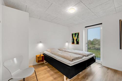 a white bedroom with a bed and a window at Luxurious 8-Person House With A Spacious Outdoor Spa - 1003 in Ringkøbing