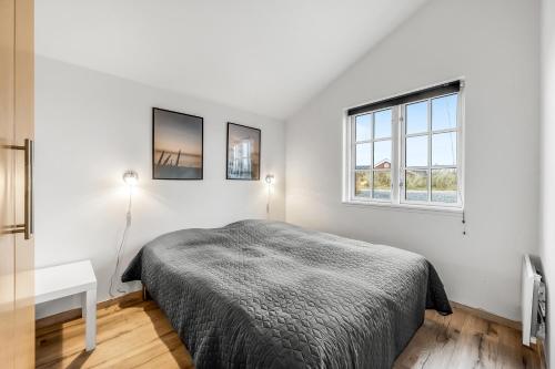a white bedroom with a bed and a window at Lovely Spa House - 1006 in Hvide Sande