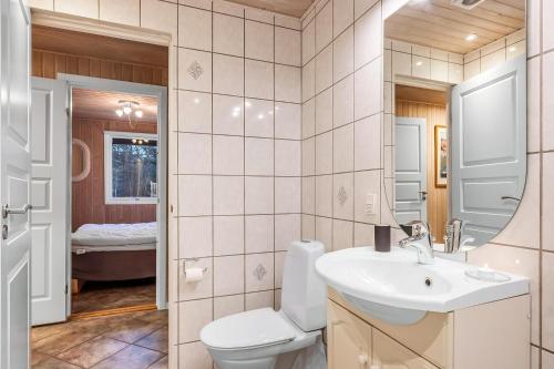 ein Badezimmer mit Toilette, Waschbecken und Spiegel in der Unterkunft Lovely 6-Person Cottage With Outdoor Sauna - 1007 in Ringkøbing