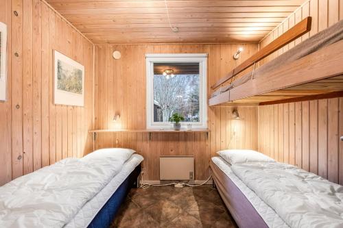ein Schlafzimmer mit zwei Etagenbetten und einem Fenster in der Unterkunft Lovely 6-Person Cottage With Outdoor Sauna - 1007 in Ringkøbing