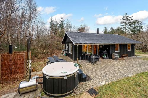 a black house with a hot tub in the yard at Lovely 6-Person Cottage With Outdoor Sauna - 1007 in Ringkøbing
