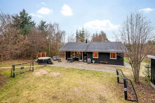 a black house with a grill in a yard at Lovely 6-Person Cottage With Outdoor Sauna - 1007 in Ringkøbing