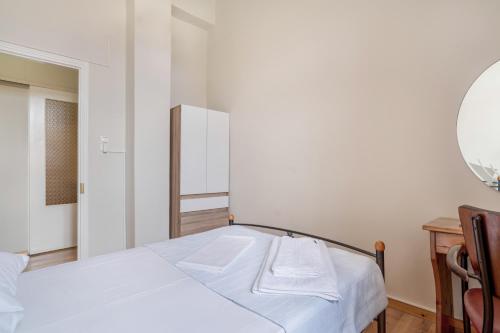 a white bedroom with two beds and a mirror at El Padre Residence in Sívros