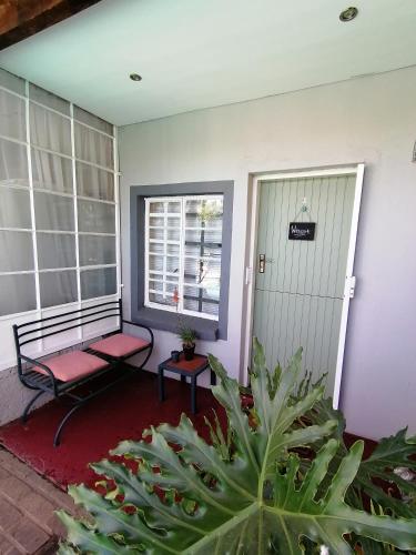 a porch with a bench and a window and plants at Hill Manor Room 2 Self catering unit in Potchefstroom