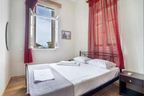 a bedroom with a bed with red curtains and a window at El Padre Residence in Sívros