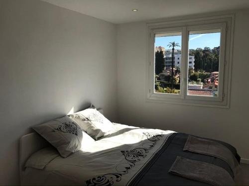 un lit dans une chambre blanche avec une fenêtre dans l'établissement Appartement à Cannes climatisé de 70 m2 à 300 m de la plage, à Cannes