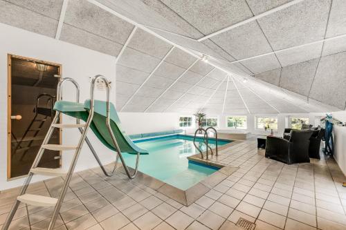 a house with a swimming pool with a ladder and a slide at Nice Pool House For 12 Persons - 1021 in Ringkøbing