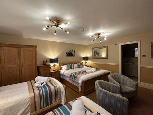 a hotel room with two beds and a chair at Chester House Guest House in Chester