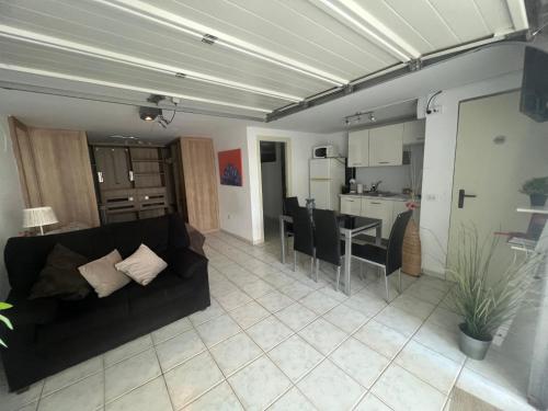 a living room with a black couch and a kitchen at LOFT Surf & Playa El Medano con WIFI Luminoso Ideal con Mascotas in El Médano