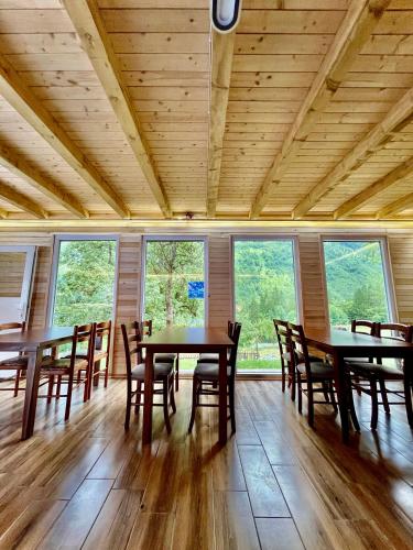 a dining room with tables and chairs and windows at Lazer Çardaku Guest House in Valbonë