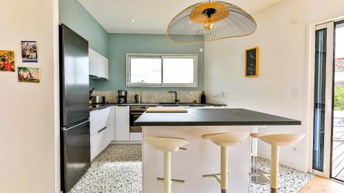 a kitchen with a black counter and stools at Villa des Loups de Mer in Talmont