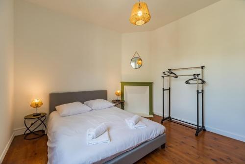 - une chambre avec un lit avec des draps blancs et 2 lampes dans l'établissement appartement Le Reflet du Port du Legue plerin, à Plérin