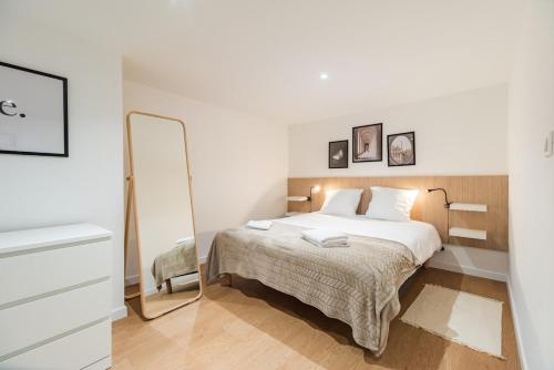 a white bedroom with a bed and a mirror at Grande maison familiale avec jardin parking et jeux in Saint-Carreuc