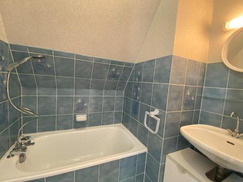 a blue tiled bathroom with a tub and a sink at Maison familiale - Plage 300m in Jullouville-les-Pins