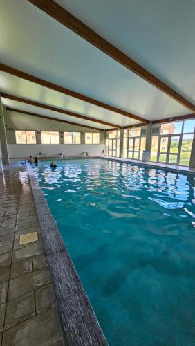 une grande piscine avec de l'eau bleue dans un immeuble dans l'établissement 7mn de Deauville Jardin Wifi Box TV, à Saint-Arnoult