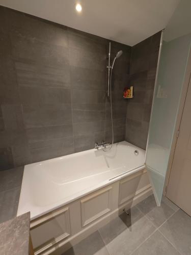 a white bath tub in a bathroom with gray tiles at Harmonie et les fées du Flavion - chambres in Onhaye