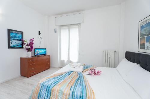 a white bedroom with a bed and a tv at Station's Apartments Bergamo in Bergamo