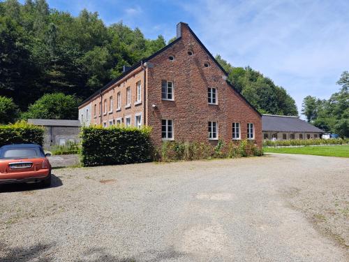 an old brick building with a car parked in front at Harmonie et les fées du Flavion - chambres in Onhaye