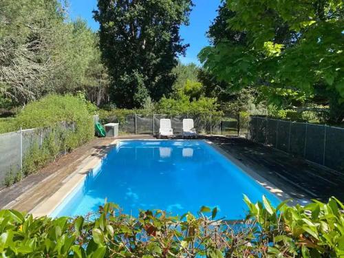 une piscine bleue avec deux chaises et une clôture dans l'établissement Gîte du Maou - Maison avec piscine, à Lesperon