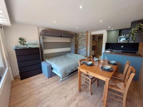 Cet appartement comprend une chambre avec une table et un lit ainsi qu'une cuisine. dans l'établissement Superbe studio à 2 pas du centre, au Bourg-dʼOisans