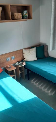 a room with two blue beds and a table at Mobil home neuf 6 personnes in La Tremblade