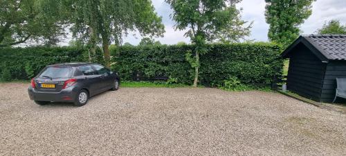 a car parked in a gravel driveway next to a hedge at Beautiful renovated Farmhouse in Ankeveen