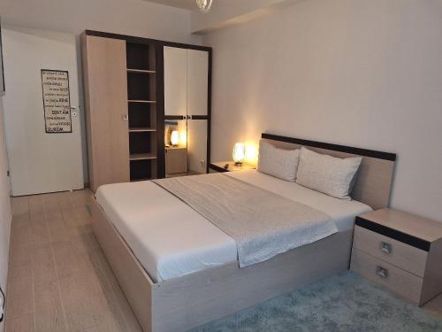 a bedroom with a large white bed and a night stand at Cazare Apartament 2 camere in Chiajna