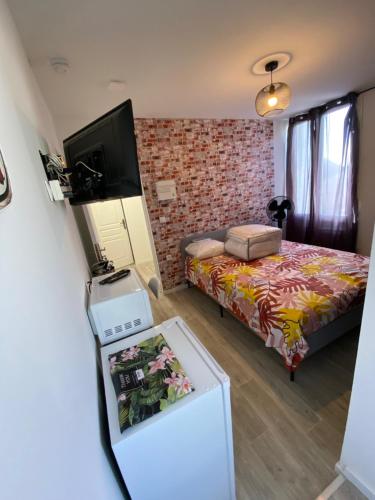 Cette petite chambre comprend un lit et une télévision. dans l'établissement Lanester Suite Home, à Lanester