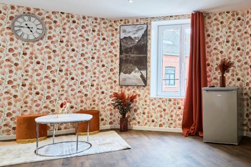 une chambre avec une table et une horloge sur un mur dans l'établissement NG Prestige l Lille l Tourcoing - Bouvines Balnéo, à Tourcoing