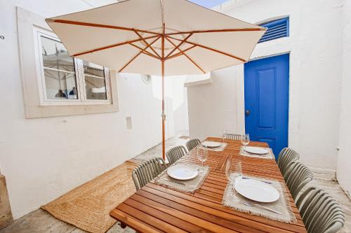 a wooden table with a large umbrella and chairs at Pateo do Mercado - 5 Quartos no Centro Histórico com Terraço in Santarém