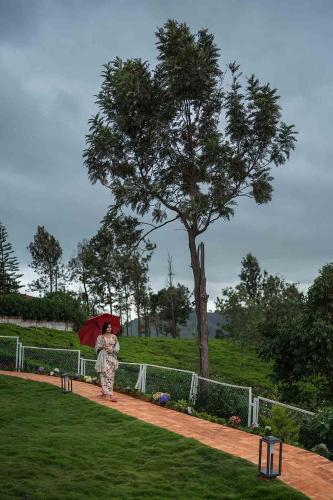 a woman walking down a path with an umbrella at LohonoStays Villa Lansdowne in Coonoor