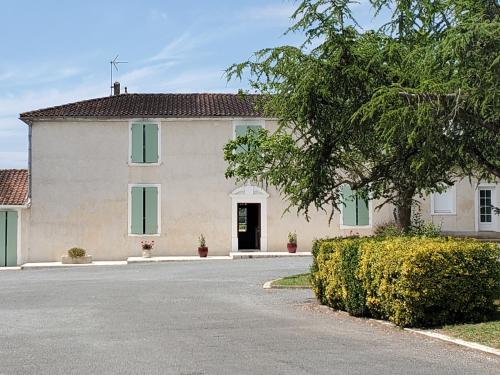 une grande maison blanche avec des fenêtres vertes et une allée. dans l'établissement Ferme de chez Piché, à Chérac