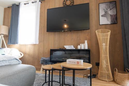 a living room with a tv and a couch and a table at L'Altima Megève - Eclat des Veriaz in Megève