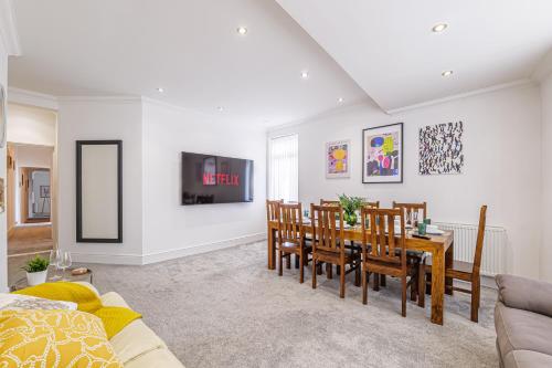 a dining room and living room with a table and chairs at Luxury 4 Bedroom Apartment Southsea - Free Parking in Portsmouth