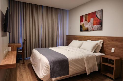 Un dormitorio con cama, escritorio y televisión. en Fantástico Flat no Serra Class em Canela-RS, en Canela