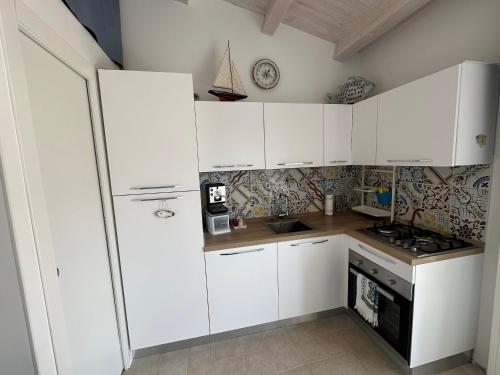 a kitchen with white cabinets and a stove at Stella di Mare in Donnalucata