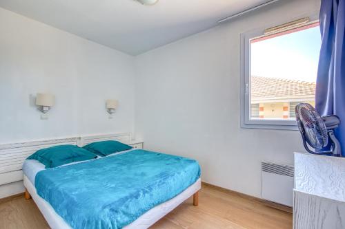 a bedroom with a bed with blue sheets and a window at Les Vertmarines in Le Verdon-sur-Mer