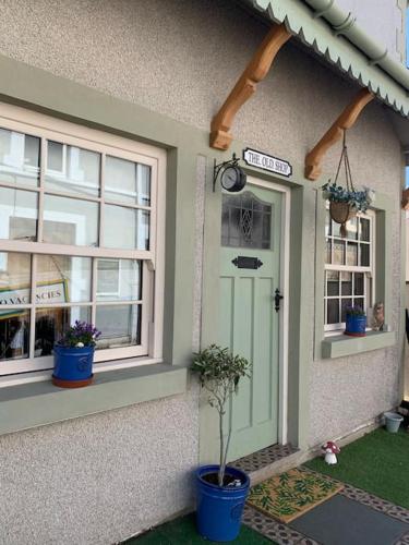 a house with a door and two potted plants on it at The Old Shop Cottage, Llandudno in Penrhyn Bay