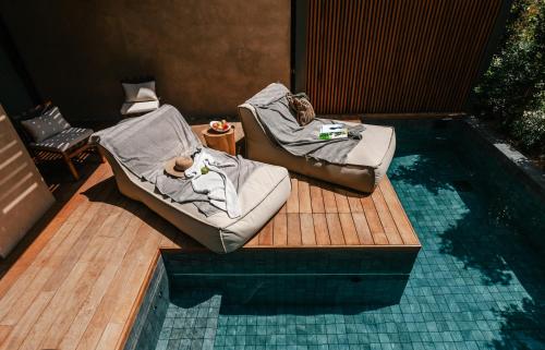 a deck with two chairs next to a swimming pool at M Boutique Hotel - Designed for Adults in Paphos City