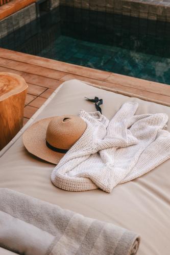 a towel and a hat sitting on a bed at M Boutique Hotel - Designed for Adults in Paphos City