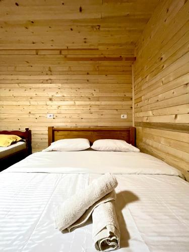 a bedroom with a bed in a wooden wall at Lazer Çardaku Guest House in Valbonë
