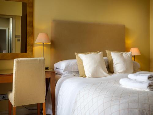 Una habitación de hotel con dos camas, un escritorio y un espejo. en Underscar - Grange, en Keswick