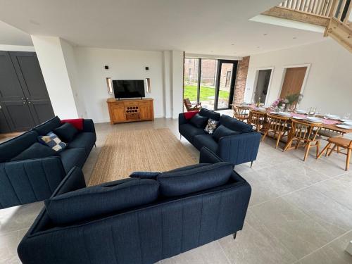 a living room with two blue couches and a television at Threshing Barn- Modern 5 Bed, 10 person, Barn Conversion in a Rural Location with Great Access in Silkstone