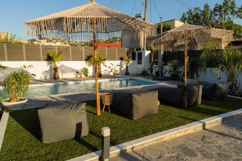 a swimming pool with an umbrella and some plants at Mezcal Private Pool Villa in Kalívia Thorikoú